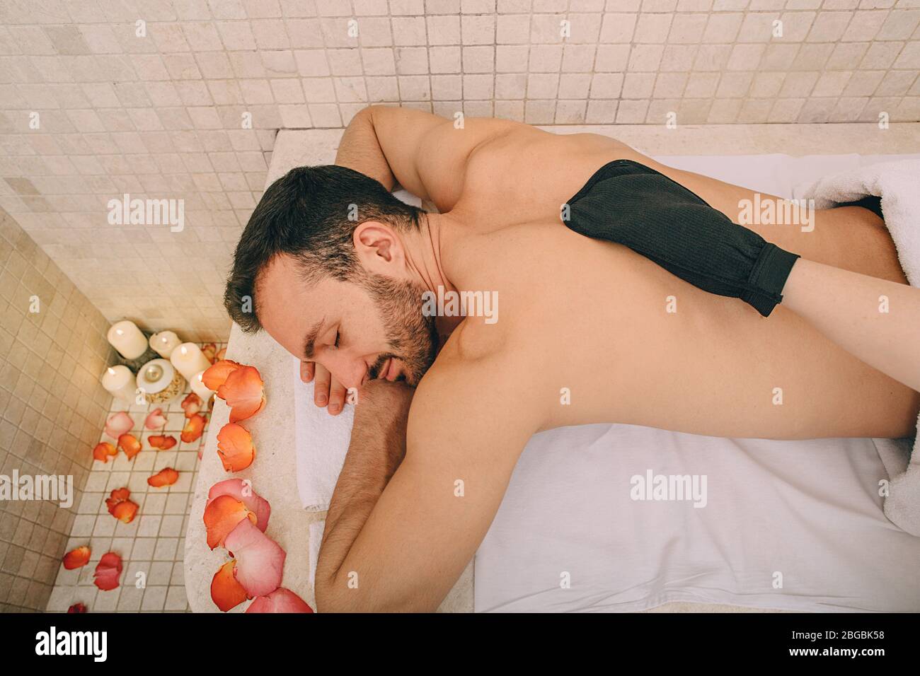Handsome man relaxes on a marble massage table in a hammam. Hammam, Turkish bath, pilling Stock Photo
