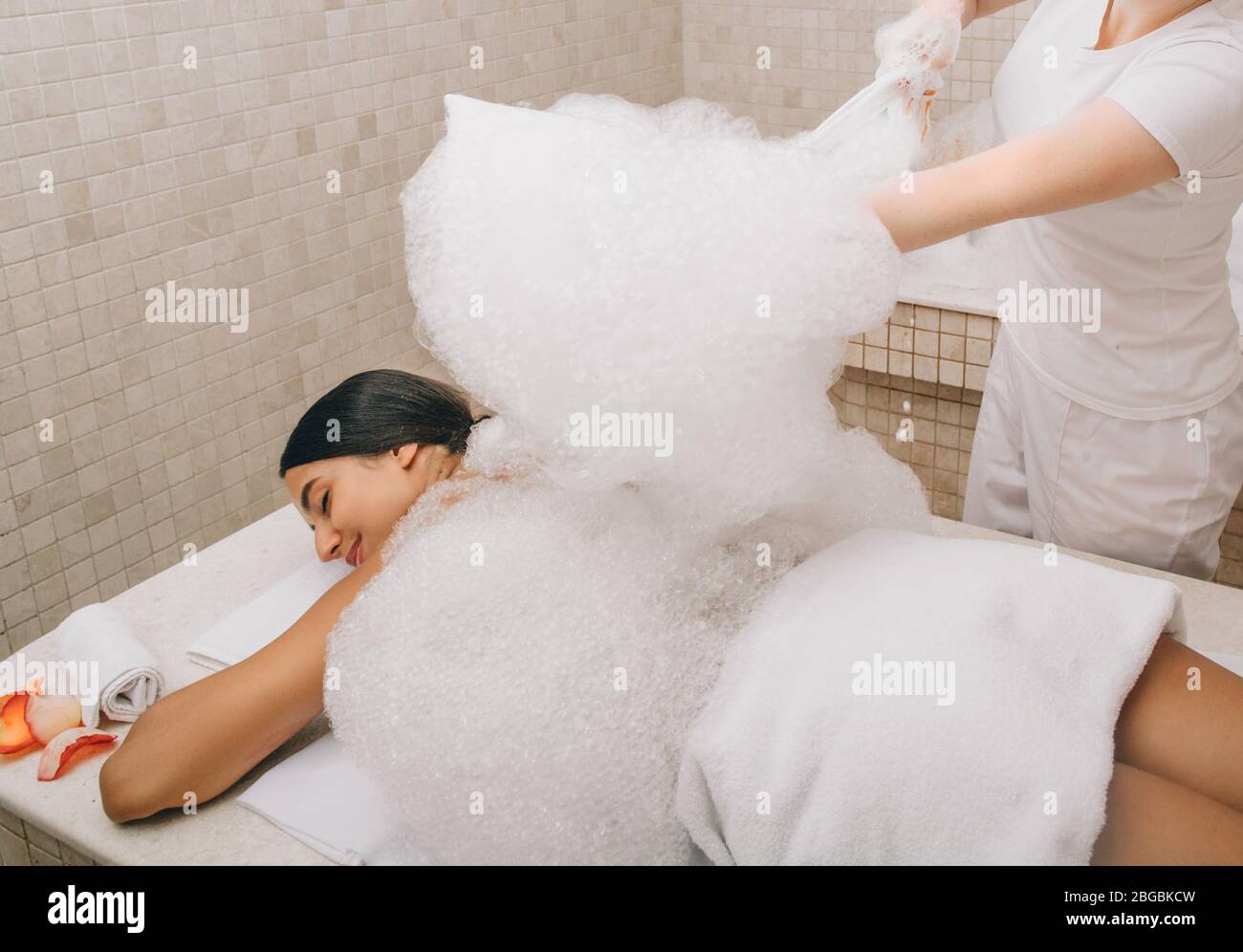Hammam worker doing foam massage on a marble hot table of Turkish bath. Hammam improving skin and stops aging process Stock Photo