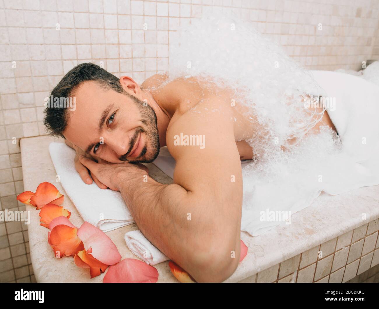 Oriental man looking into the frame during a foamy massage in a hammam . Traditional turkish bath Stock Photo