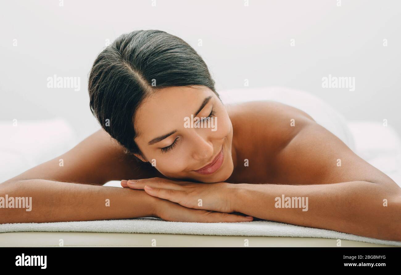Mixed race woman relaxes on massage table after relaxing in spa and massage. Stock Photo
