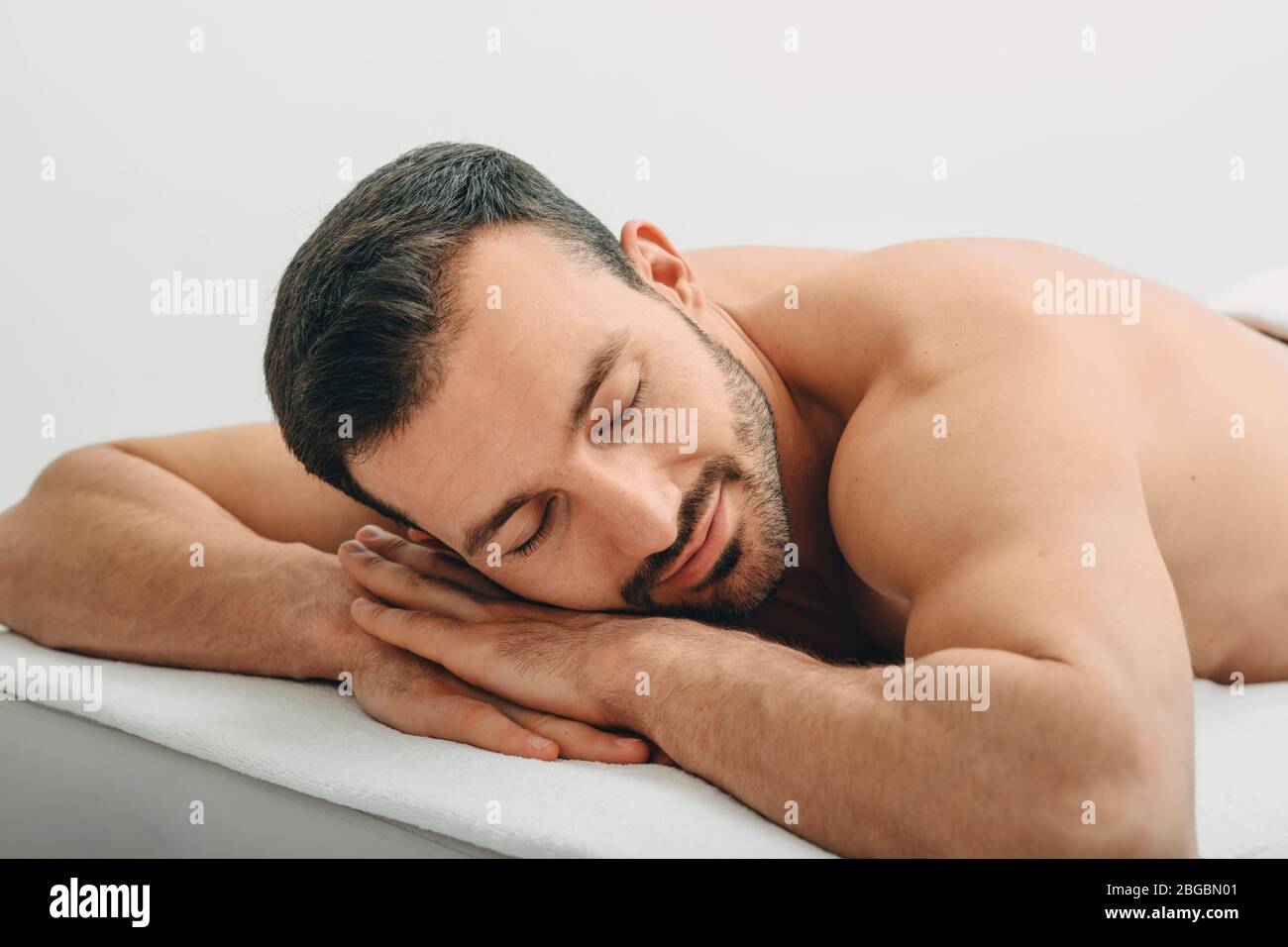 Caucasian man relaxes on massage table after relaxing in spa and massage. Stock Photo
