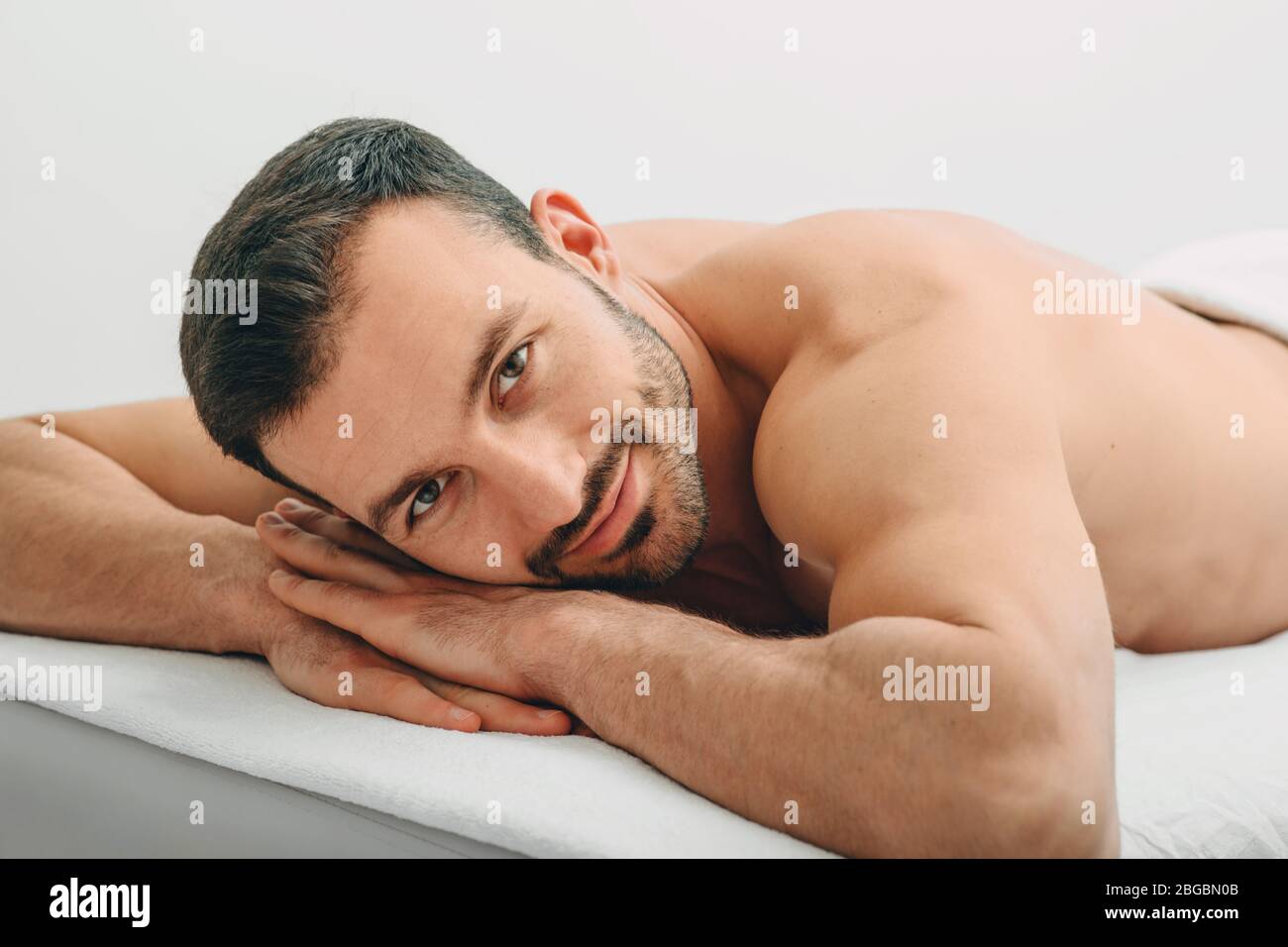 Portrait of a brunette man lying on a massage table, who is smiling, looking at the camera after massage. Spa and resort Stock Photo