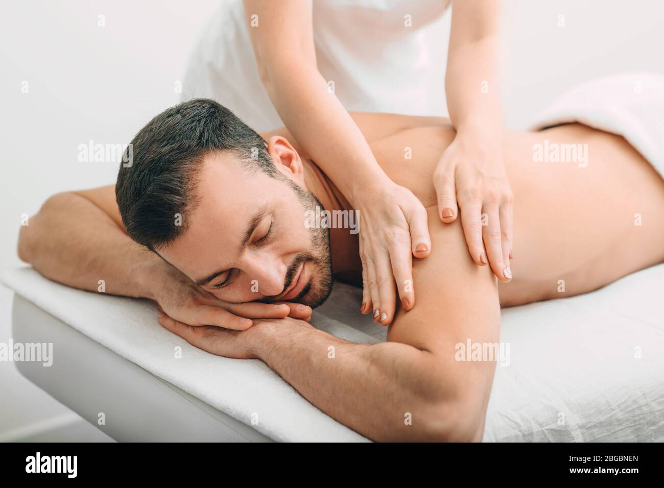 handsome man enjoying a back massage, weekend spa. mixed race man relaxes while back massage Stock Photo