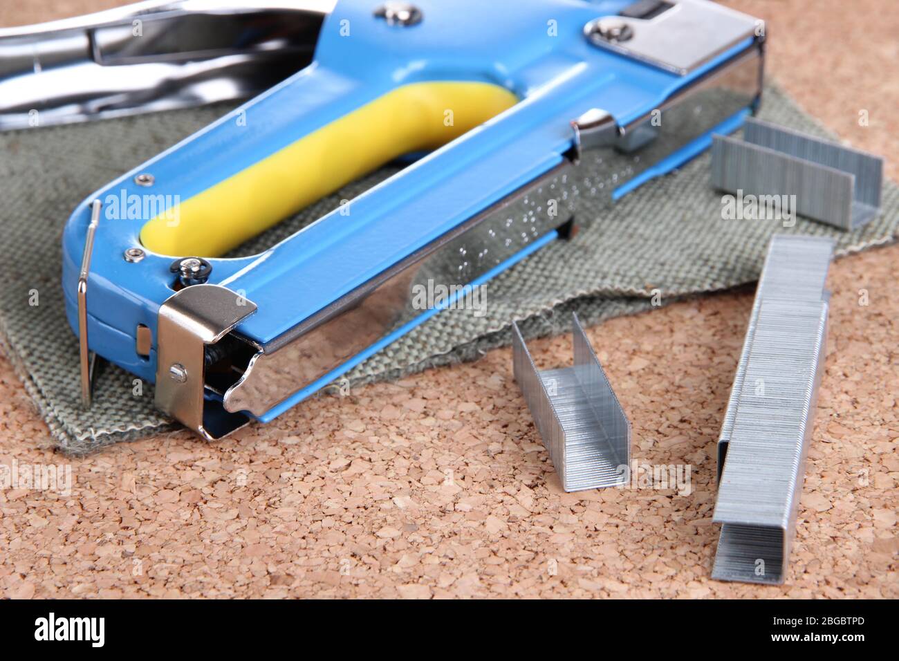 Construction stapler and staples on cork board close up Stock Photo