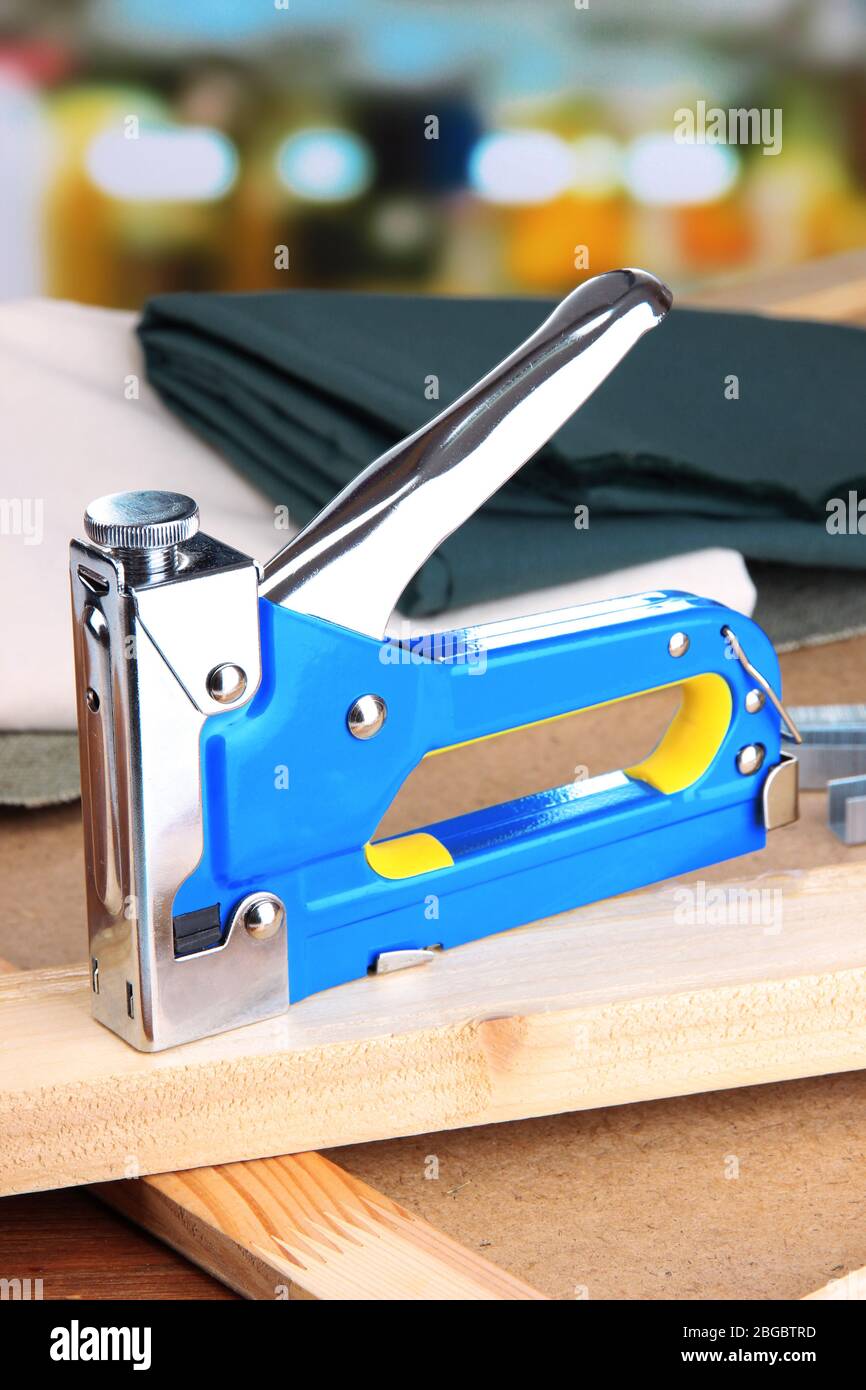 Construction stapler with fabric on cork board on bright background