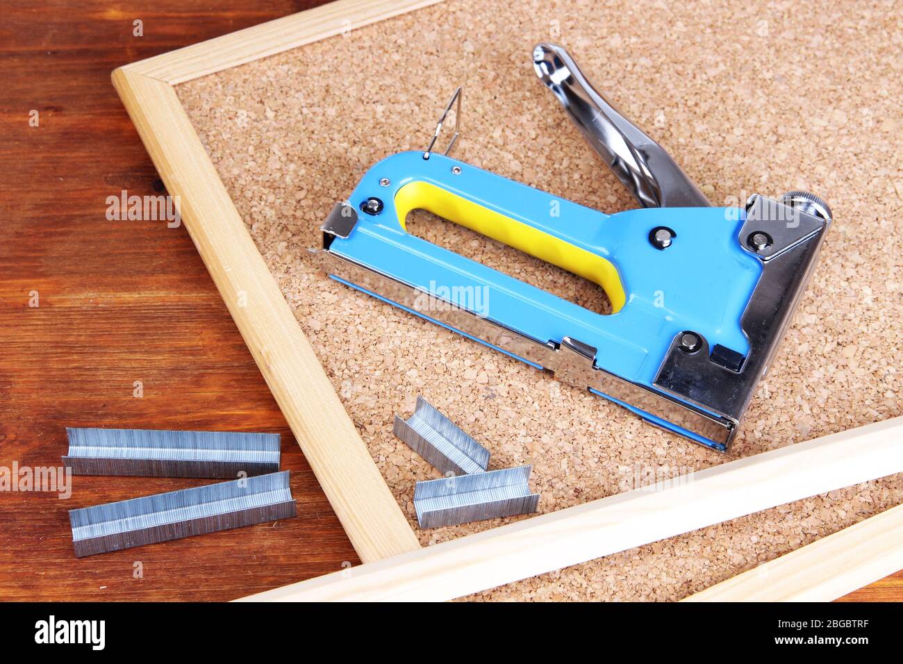 Construction stapler and staples on cork board close up Stock