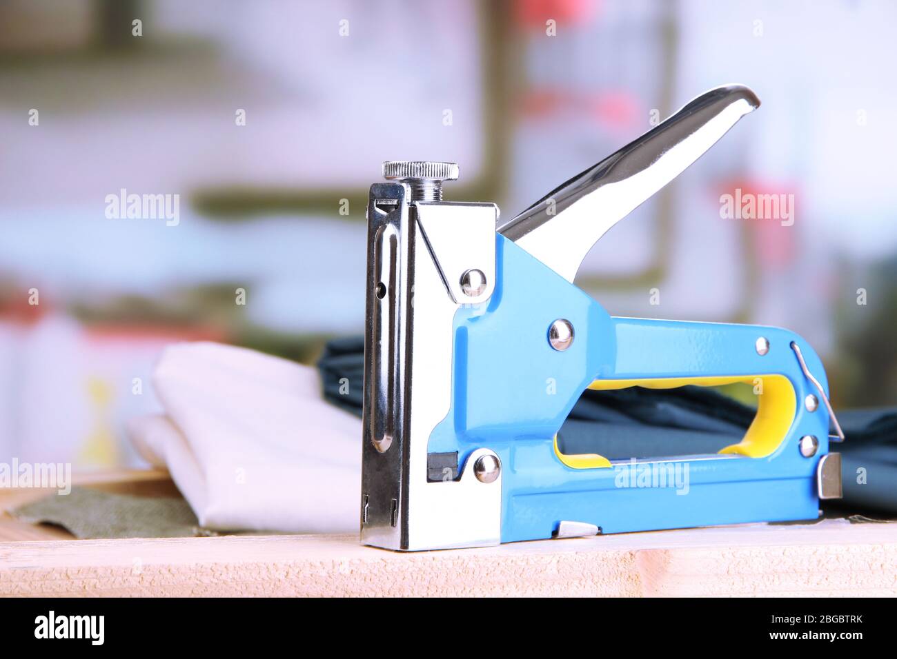 Construction stapler with fabric on cork board on bright background