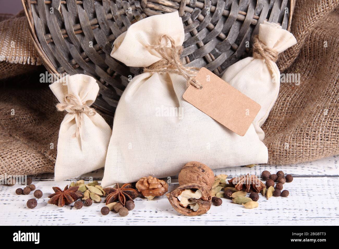 Sacks full with spices, on wooden table, on sackcloth background Stock Photo