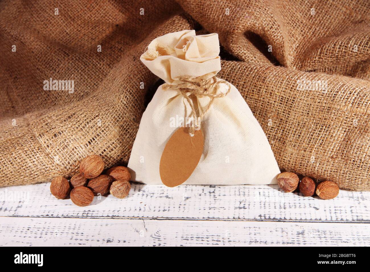 Sack full with spices, on wooden table, on sackcloth background Stock Photo