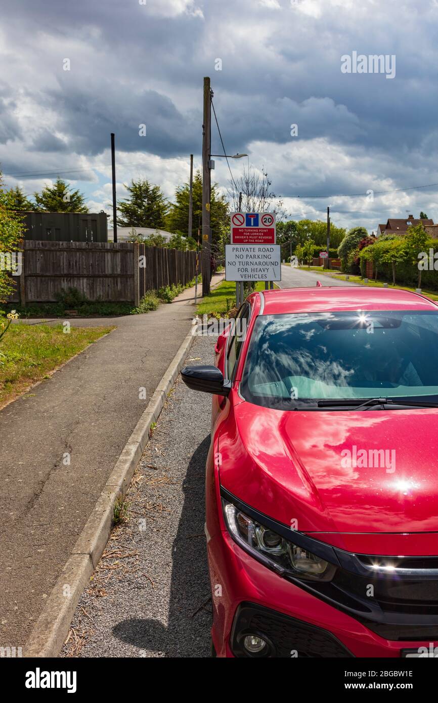 A Red Honda Civic parked at the entrance to a private road with red