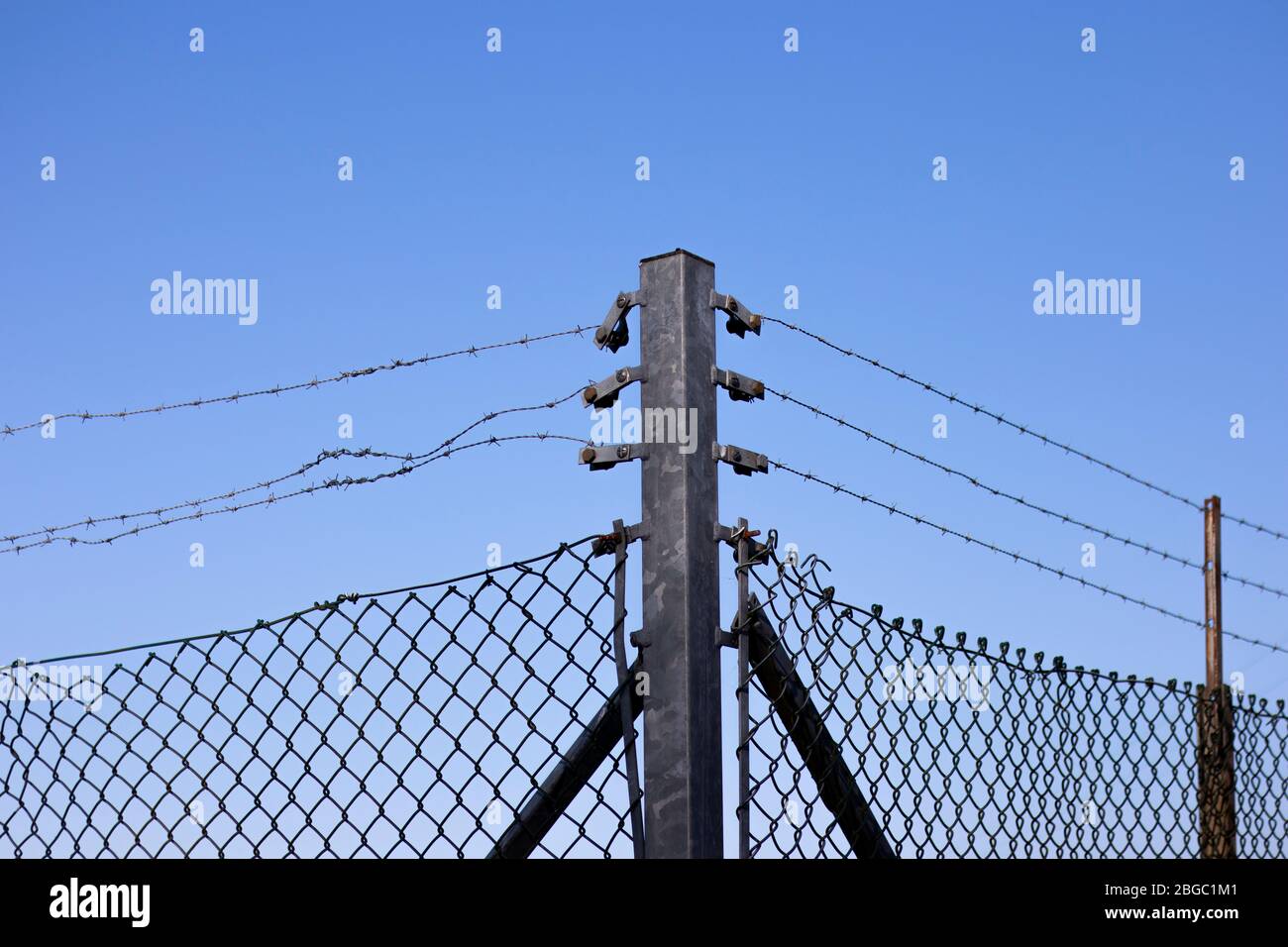 Hot dipped galvanised post and barbed wired mesh fence providing security to farmland in rural Hampshire Stock Photo