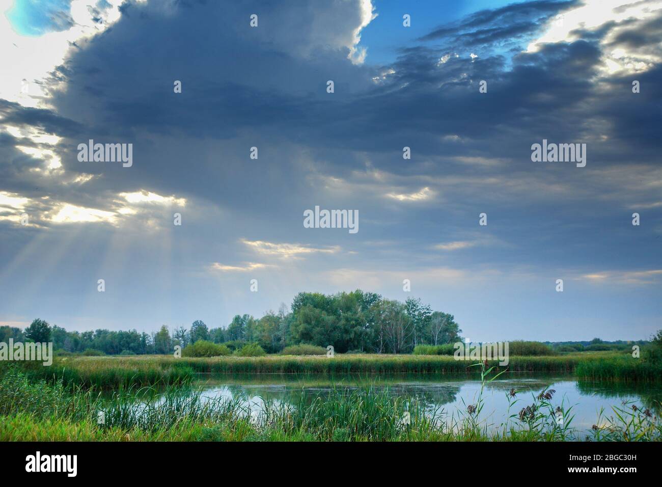 Storm dramatic clouds over a quiet forest lake. Gloomy clouds. Soft focus Stock Photo