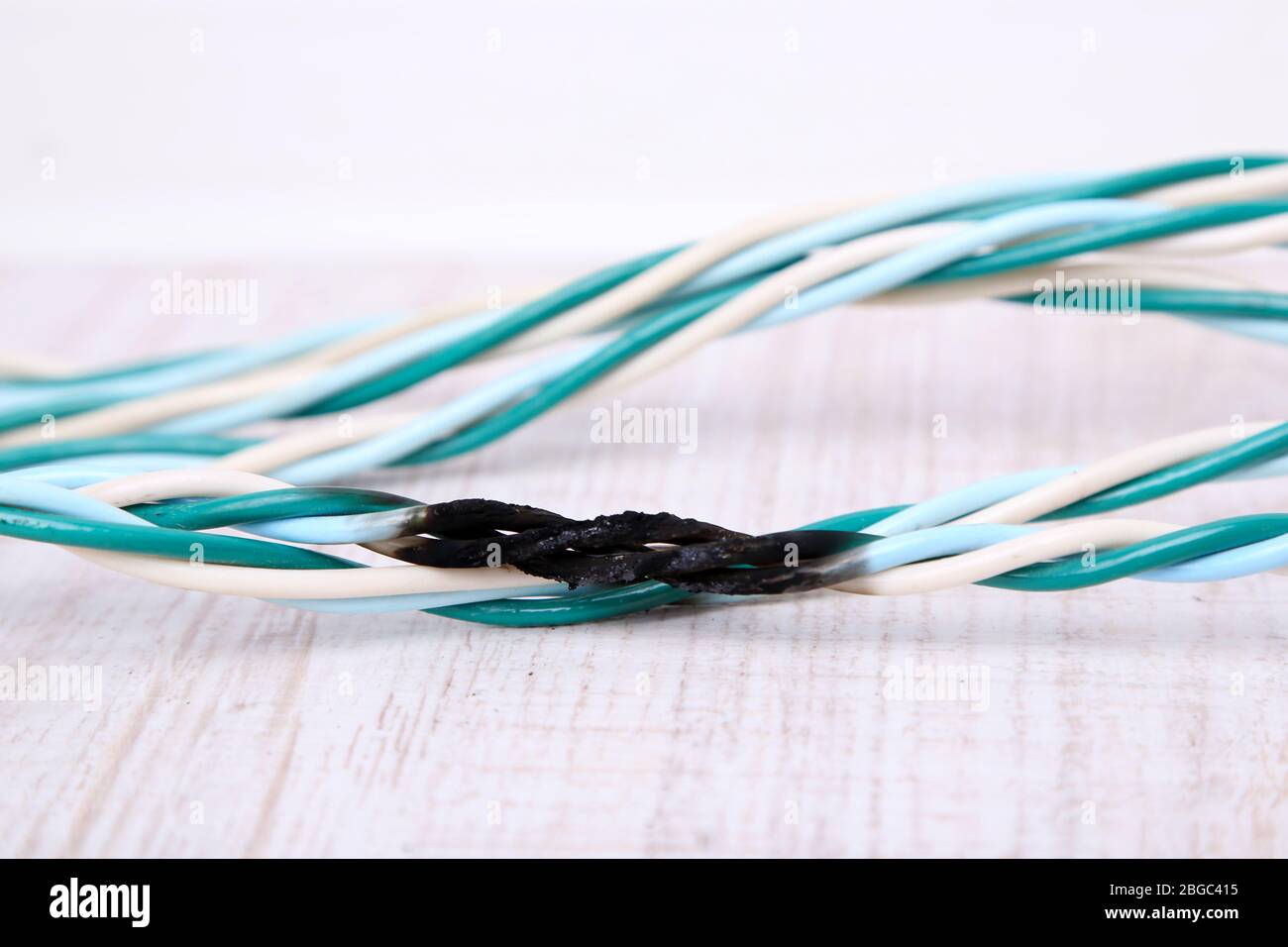 Short circuit, burnt cable, on color wooden background Stock Photo - Alamy