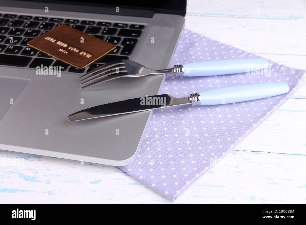 Credit card with fork and knife on computer keyboard on table close up ...