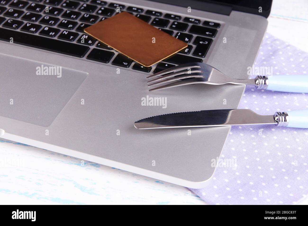Credit card with fork and knife on computer keyboard on table close up ...