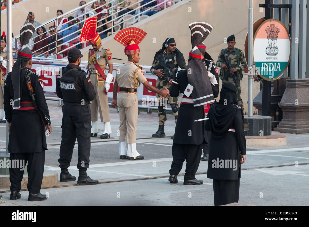 Indian and Pakistani soldiers shake hands at the Wagah Border Ceremony on the border between Pakistan and India. Stock Photo