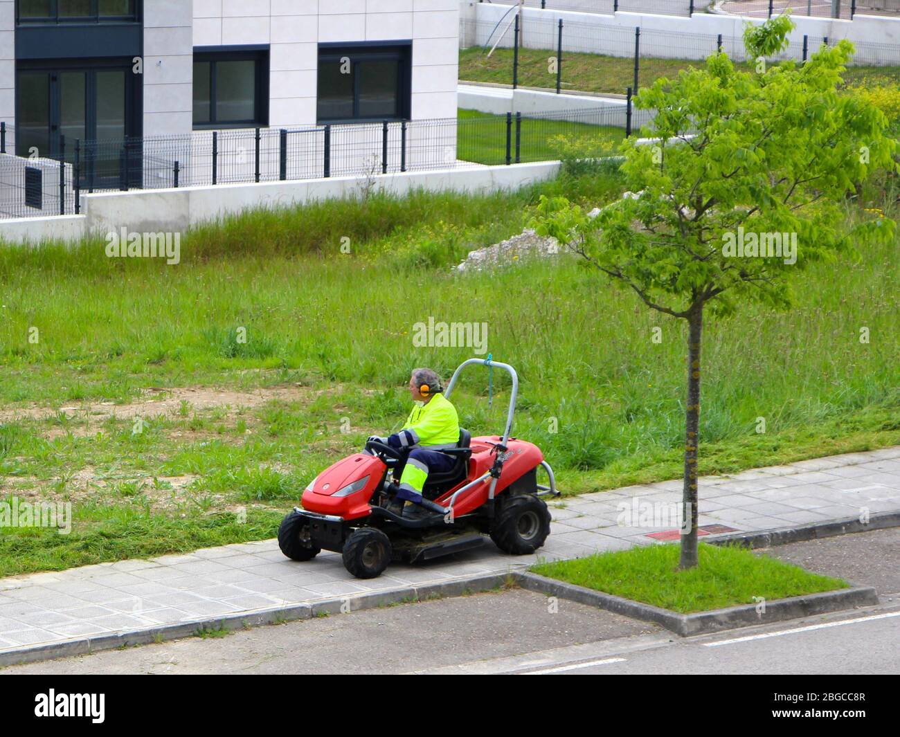 Ride on lawn mower being driven by a council worker wearing ear