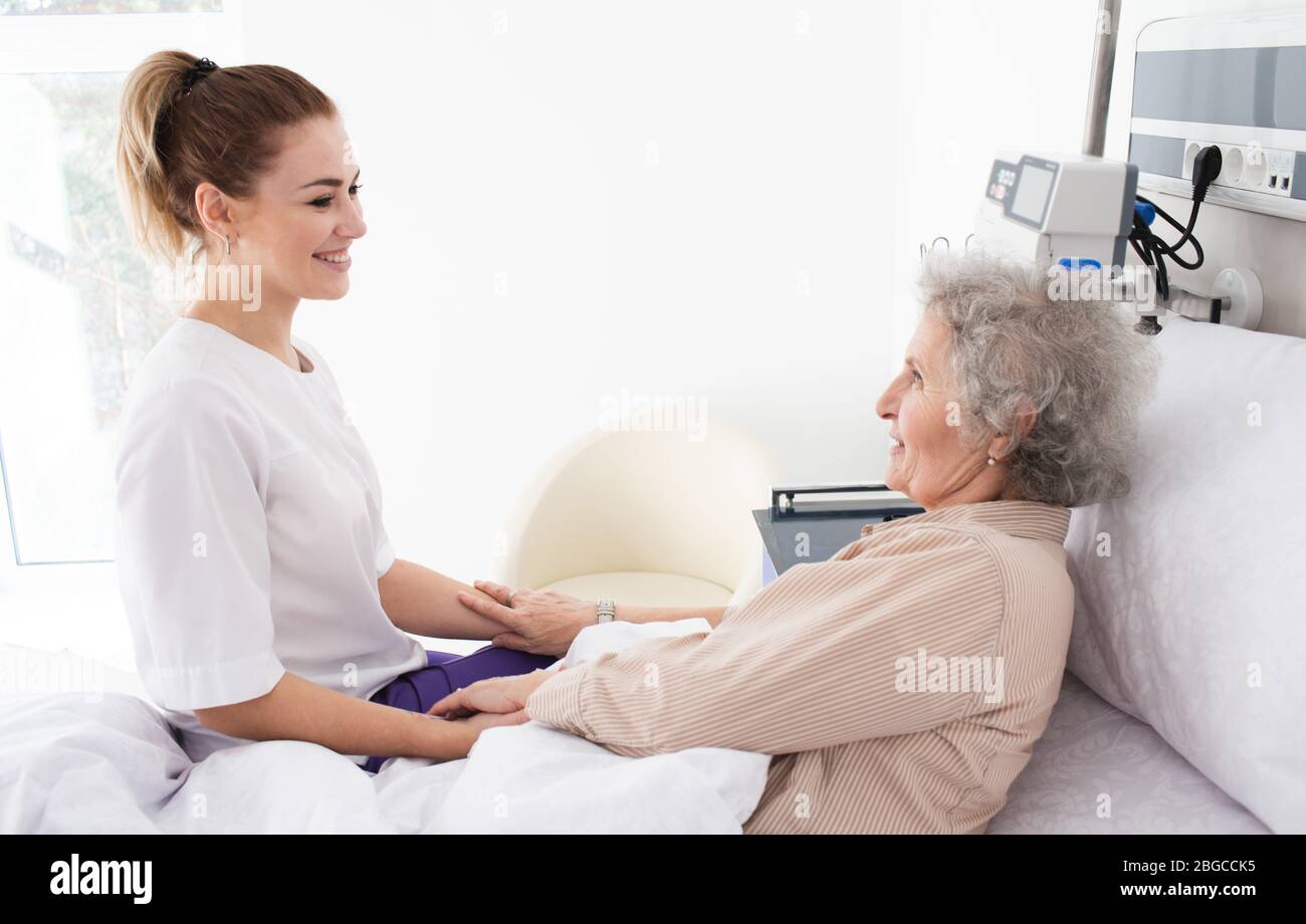 Woman with Alzheimer's disease lying in bed receives nurse care. Treating and caring for the elderly with Alzheimer's disease Stock Photo