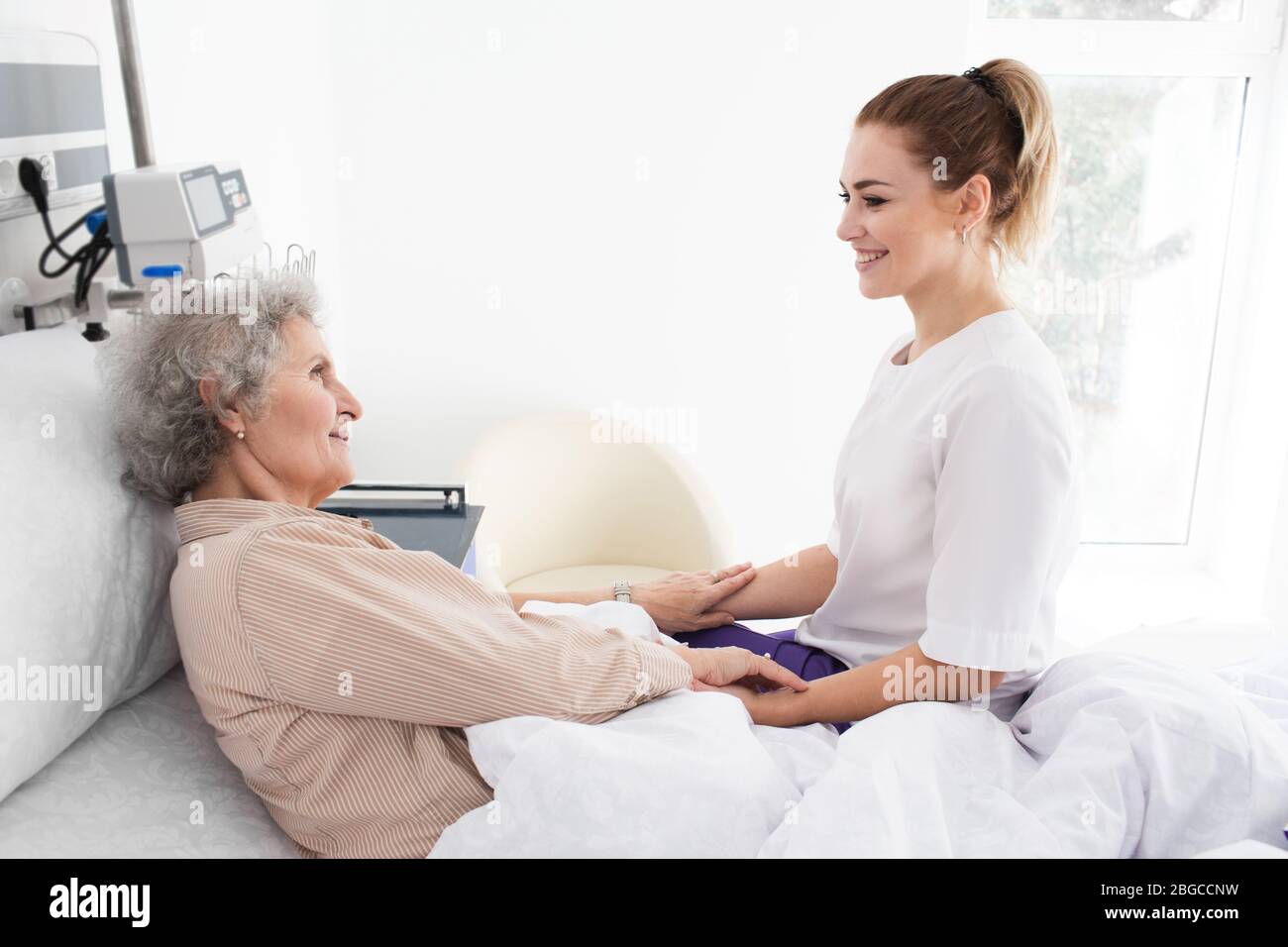 Woman with Alzheimer's disease lying in bed receives nurse care. Treating and caring for the elderly with Alzheimer's disease Stock Photo