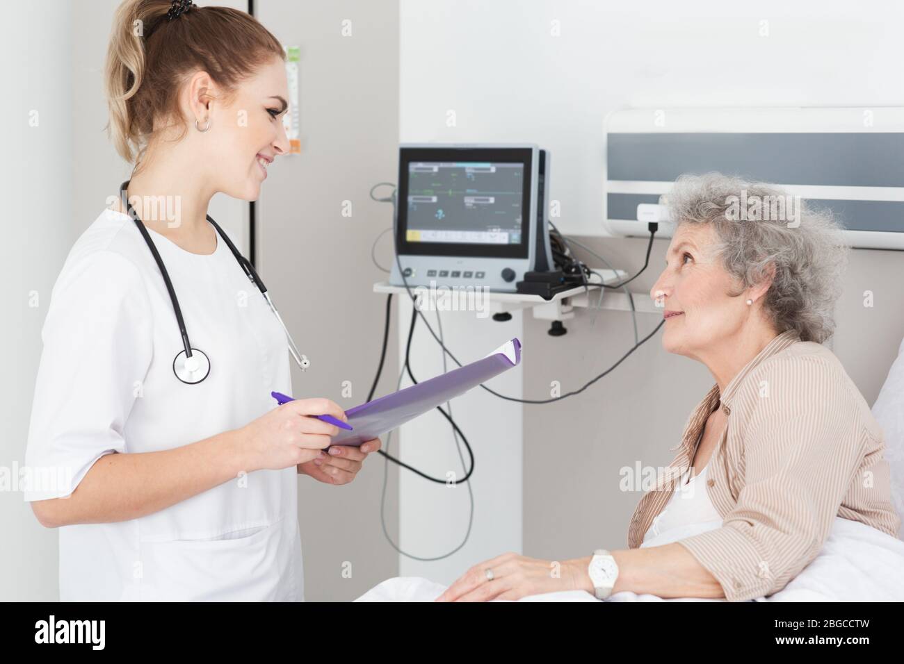 Woman with Alzheimer's disease lying in bed receives nurse care. Treating and caring for the elderly with Alzheimer's disease Stock Photo