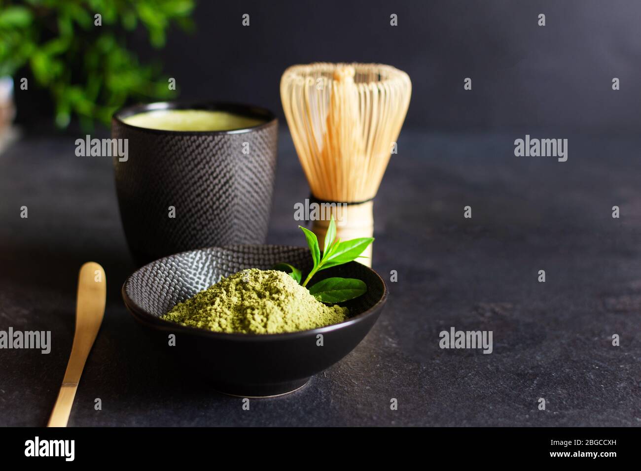 Organic green matcha tea and tea accessories on black background. Japanese tea ceremony concept. Chashaku spoon and chasen bamboo whisk for brewing ma Stock Photo