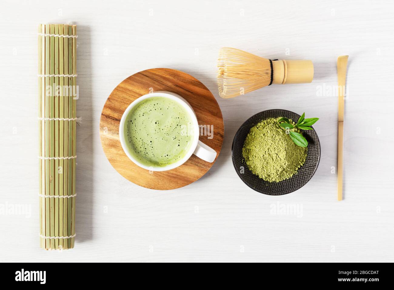 Green matcha tea latte and tea accessories on white wooden background top view. Japanese tea ceremony concept. Chashaku spoon and chasen bamboo whisk Stock Photo