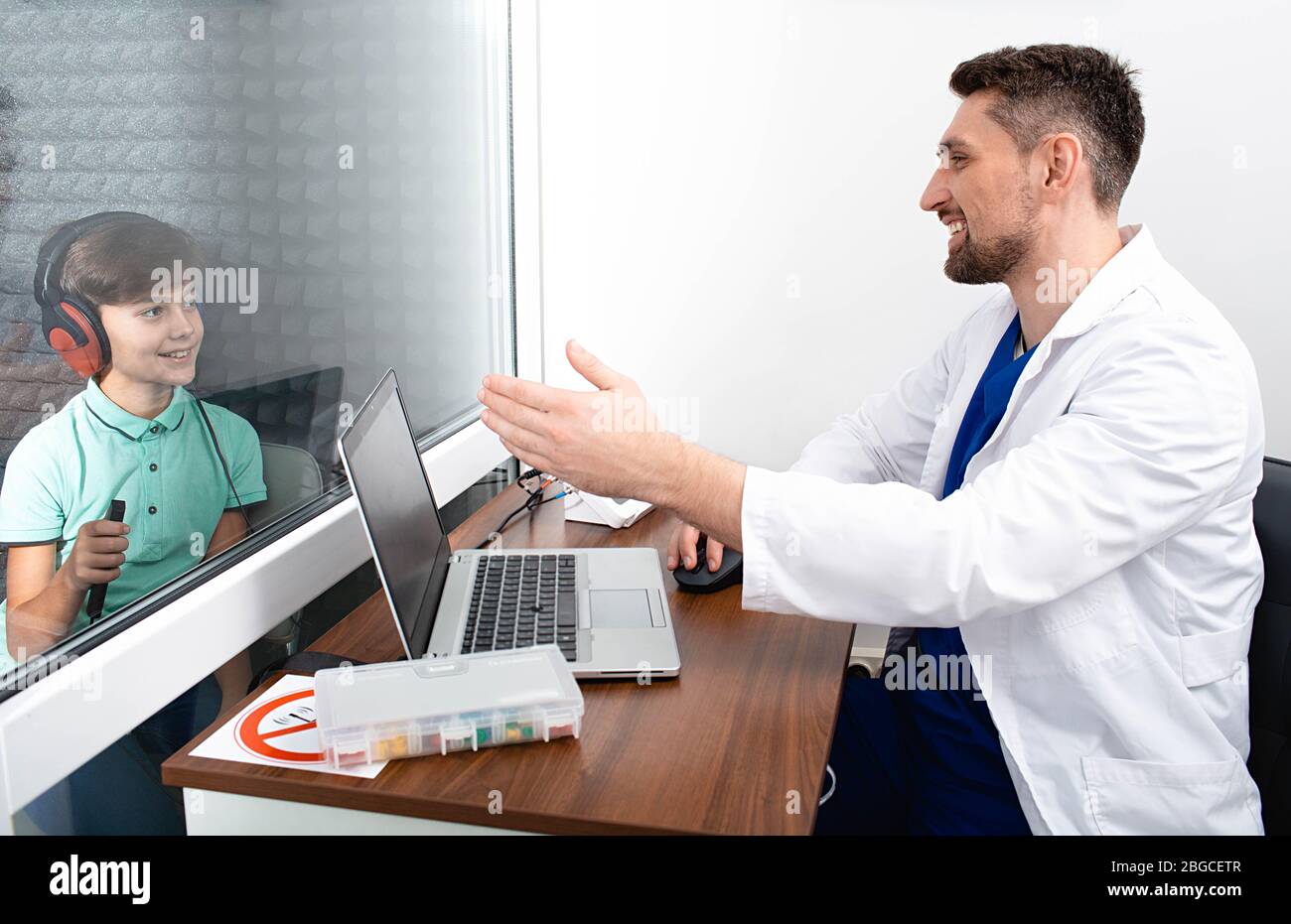 audiometry test. cute mixed race boy sitting at soundproof cabin and doing hearing test Stock Photo