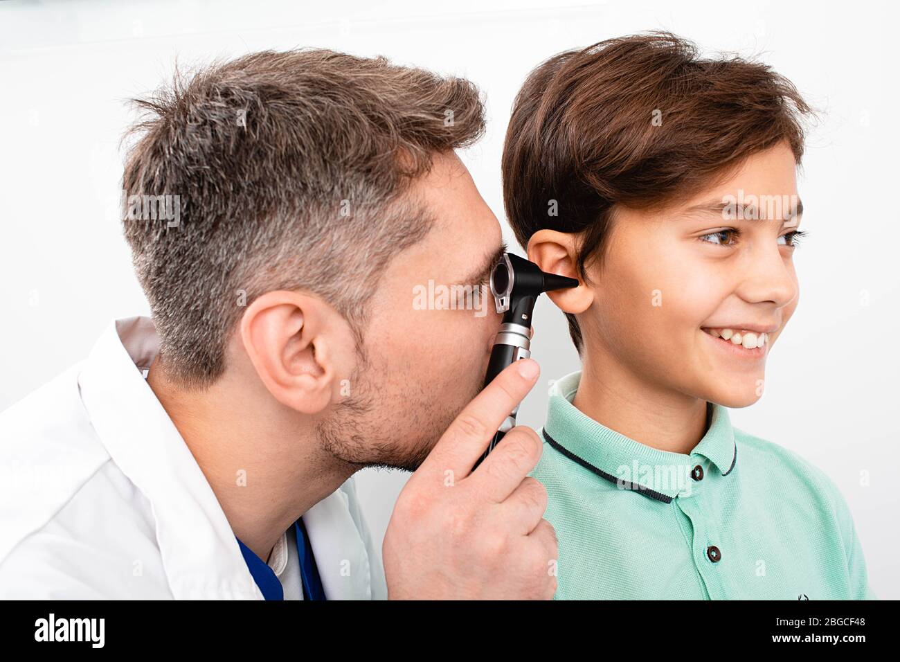 Pediatrician examining little mixed race child with otoscope, hearing exam of child Stock Photo