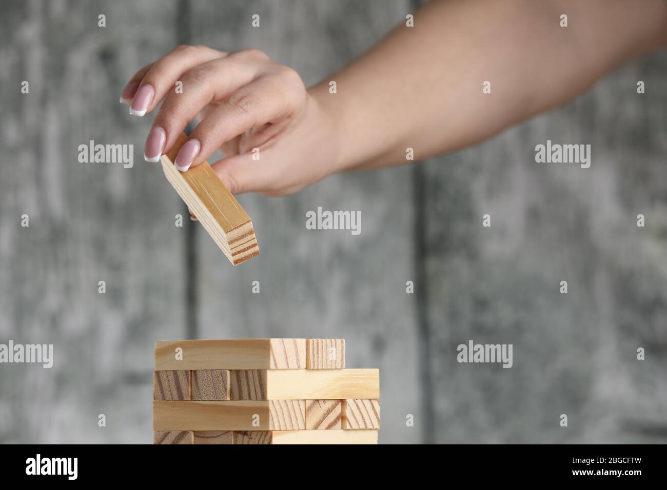 Girl hand putting wooden bricks on a table. Tower construction game. Stock Photo
