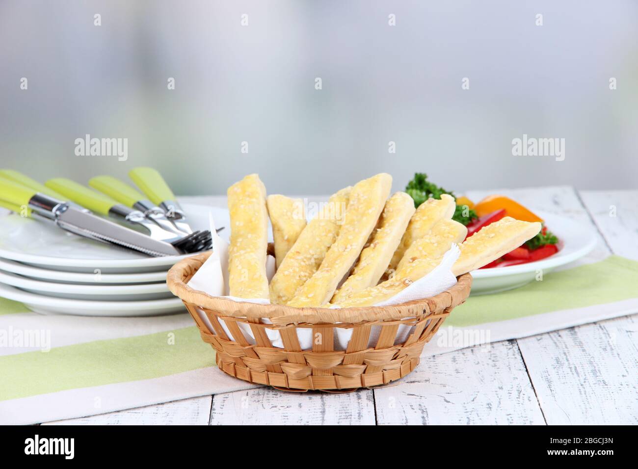 Bread sticks in wicker basket on wooden table on light background Stock  Photo - Alamy
