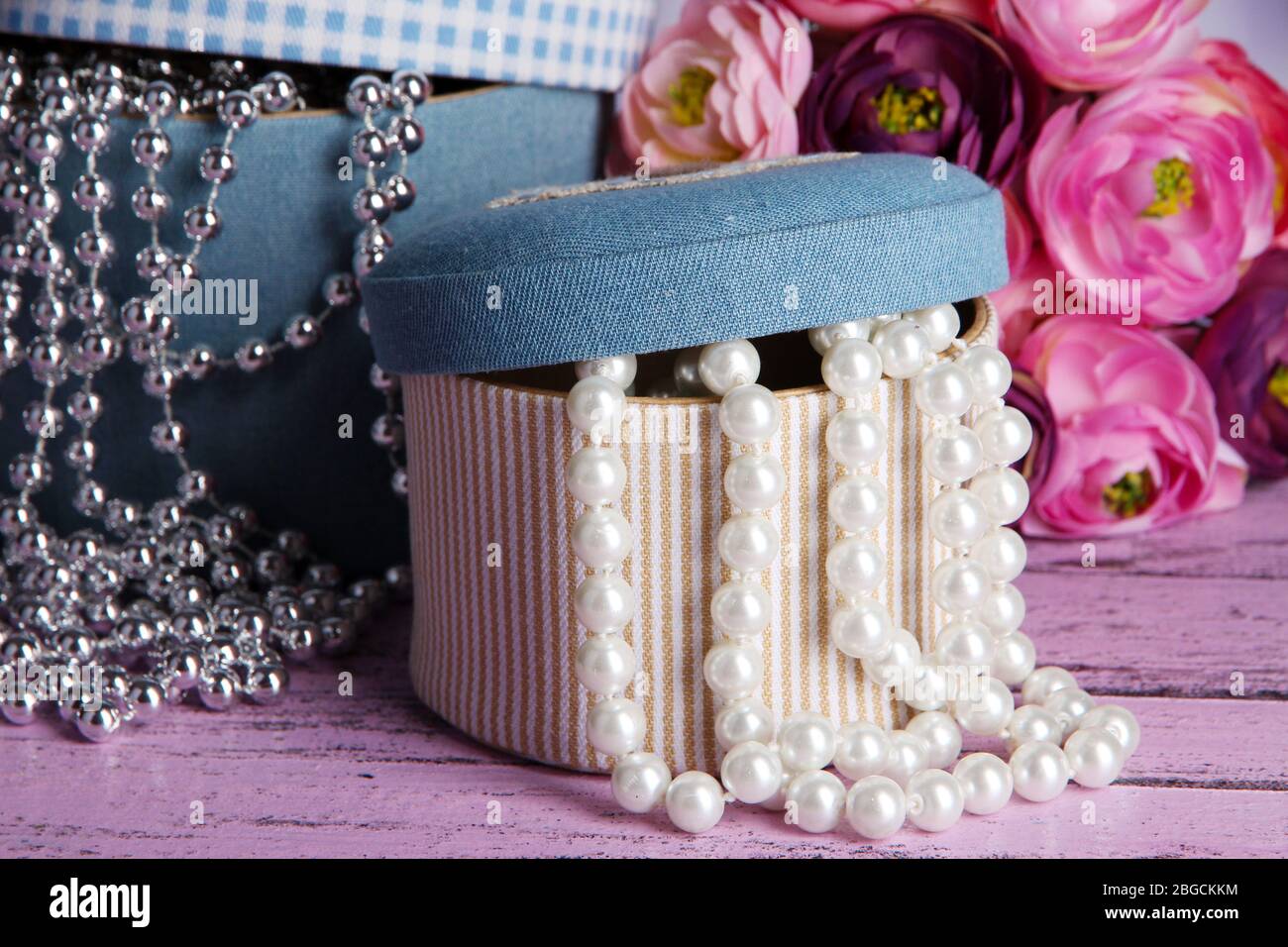 Decorative boxes with beads and flowers on wooden background Stock Photo