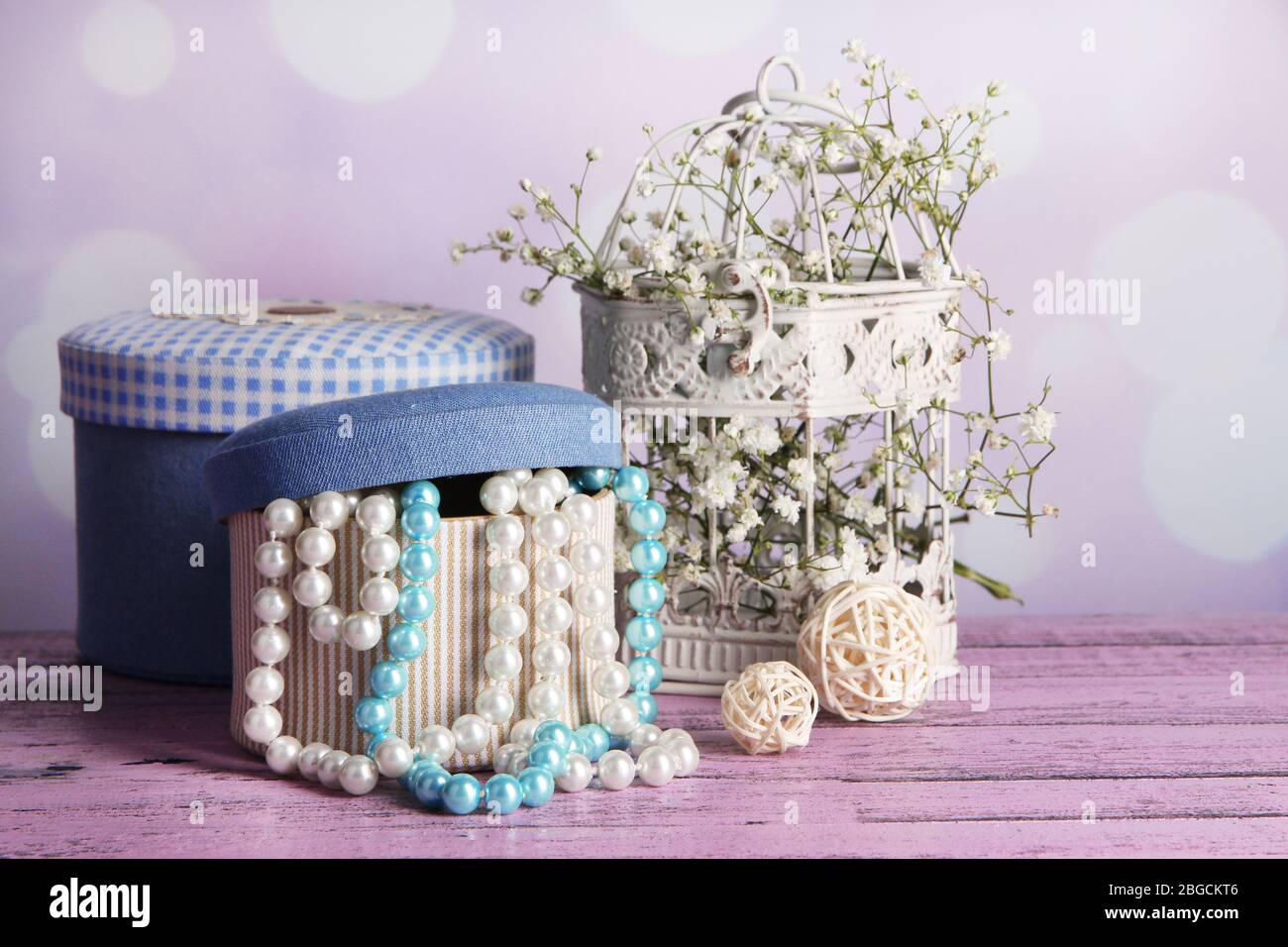 Decorative boxes with beads and flowers on table on bright background Stock Photo