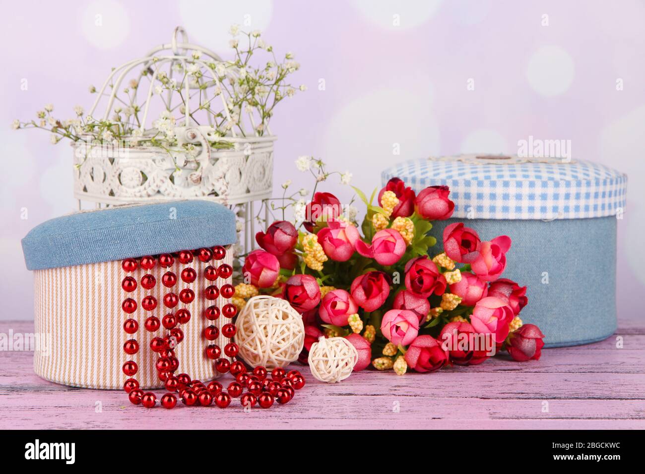 Decorative boxes with beads and flowers on table on bright background Stock Photo