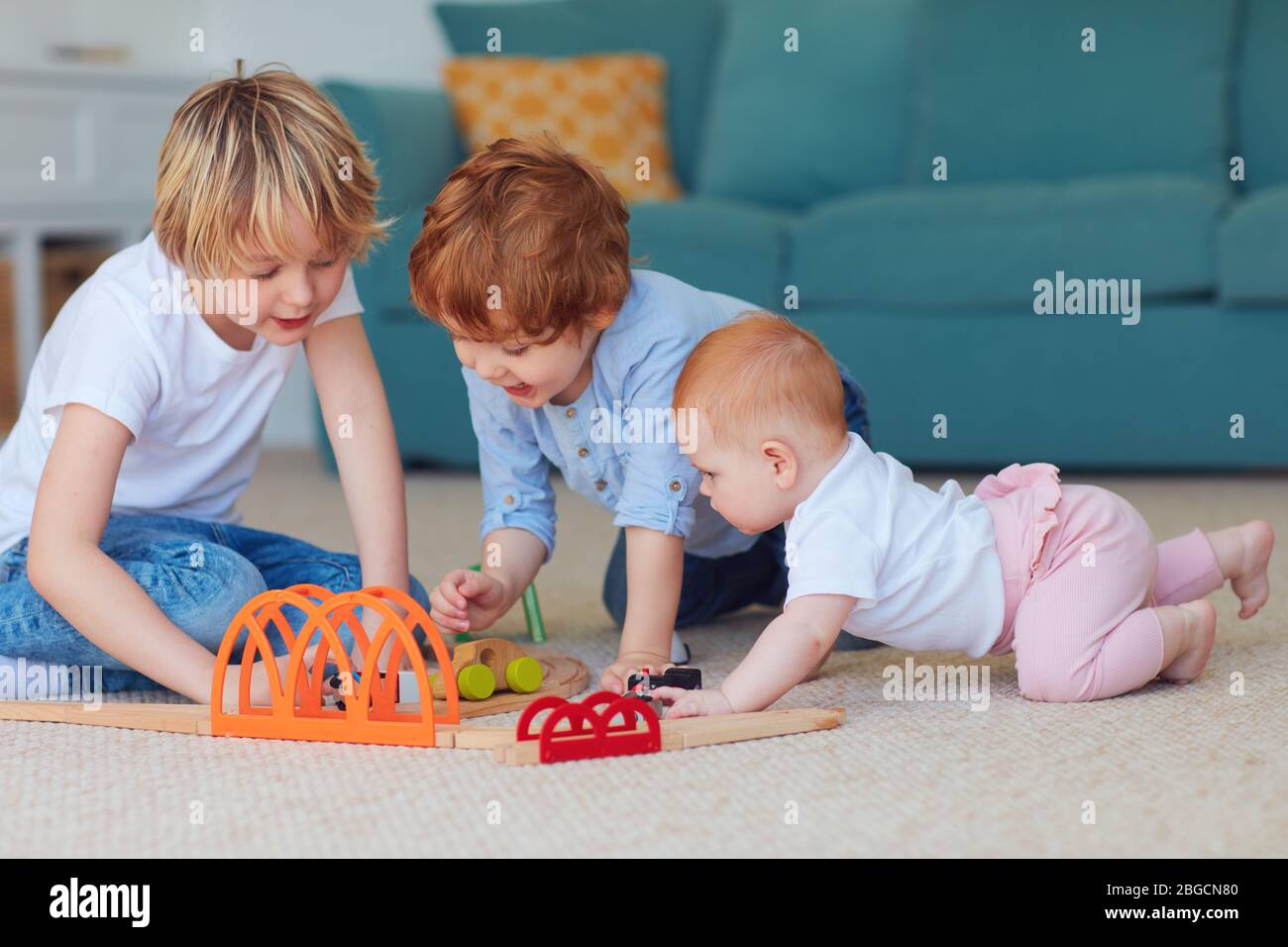 cute kids, siblings playing toys together on the carpet at home Stock