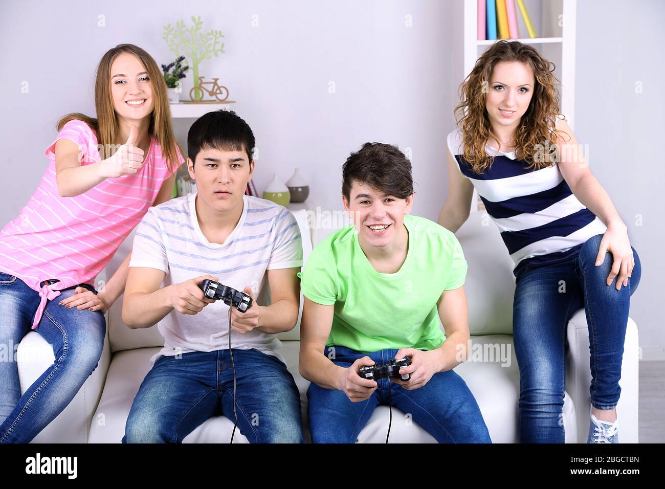 Excited multiethnic teen friends enjoying video games, free time at home, Stock image