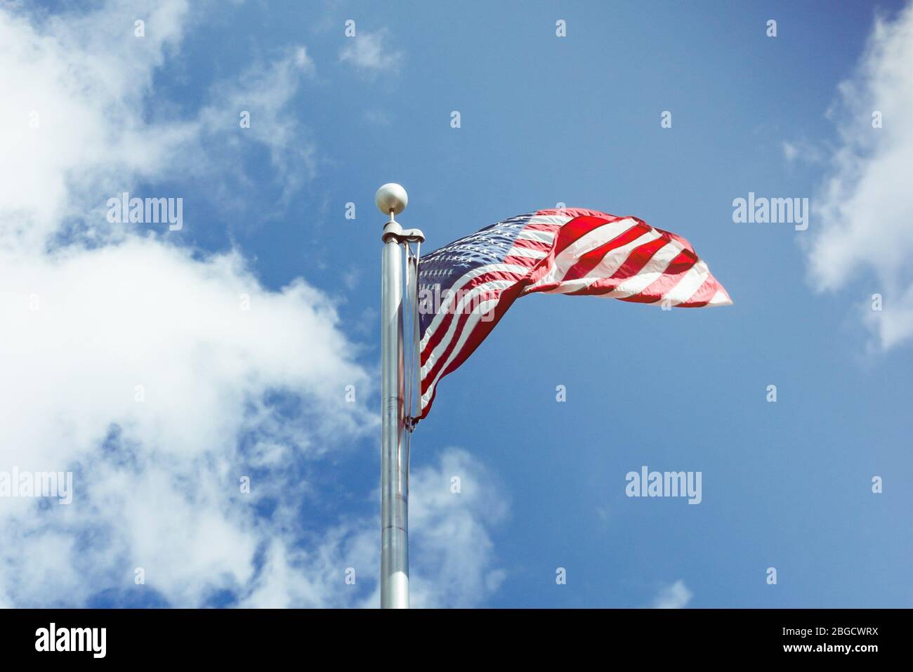 American flag against a blue sky with white clouds Stock Photo - Alamy