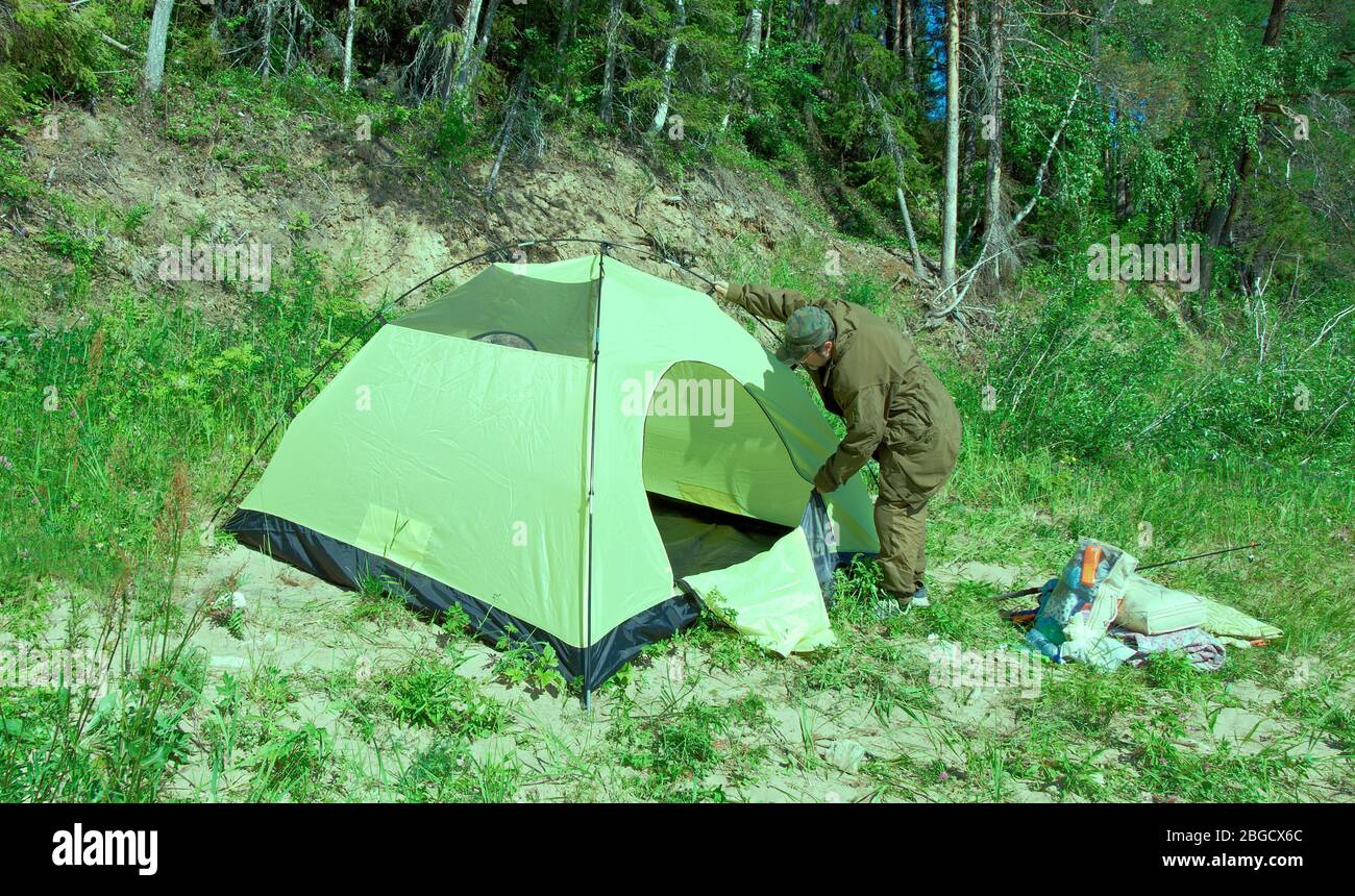 man setting up a tent.Russian taiga Stock Photo