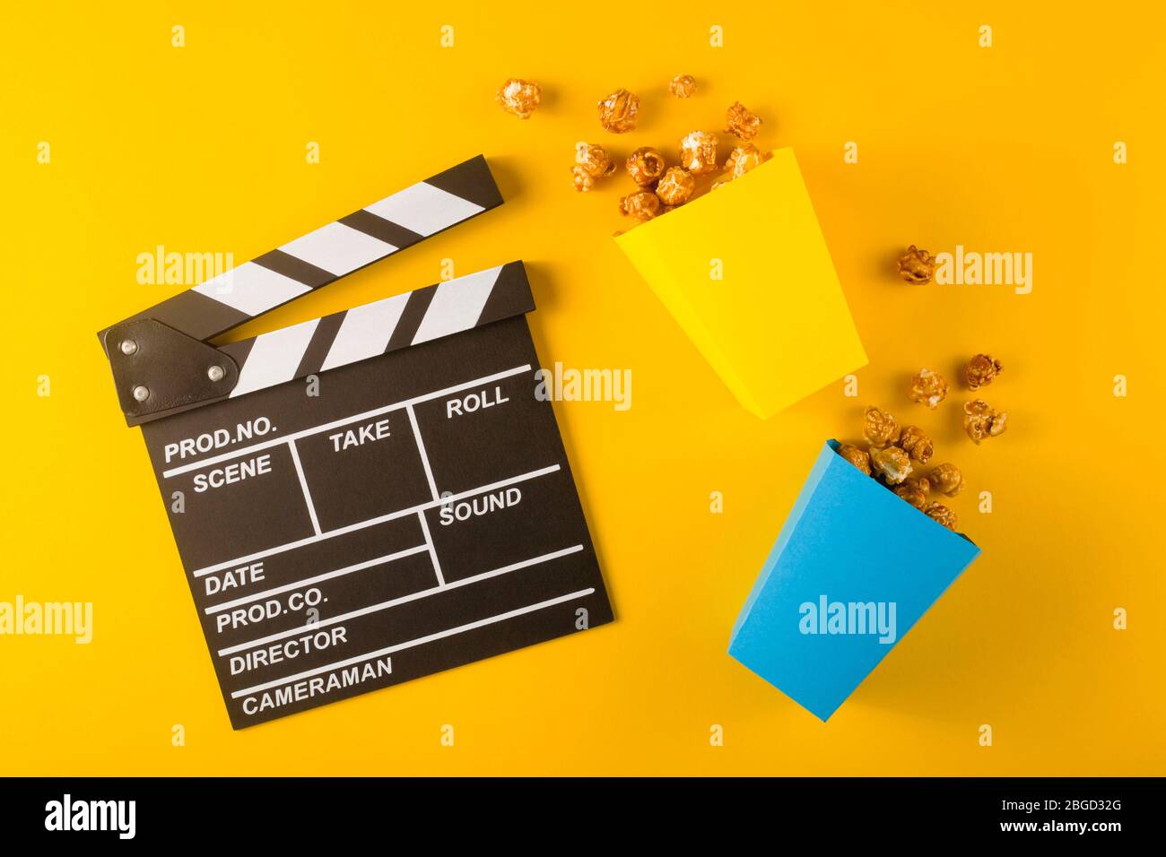 Popcorn and clapperboard on yellow background. Top view Stock Photo