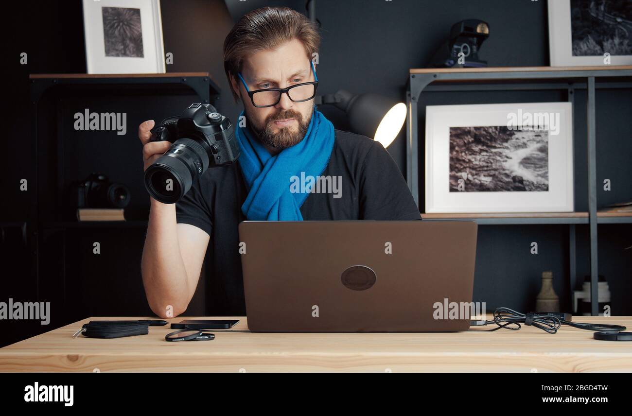 Photographer holding camera looking laptop Stock Photo