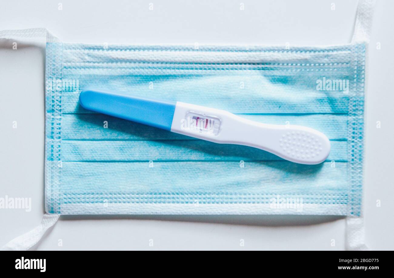Positive pregnancy test on a face mask. Expecting during pandemic. Healthy pregnancy. Stock Photo
