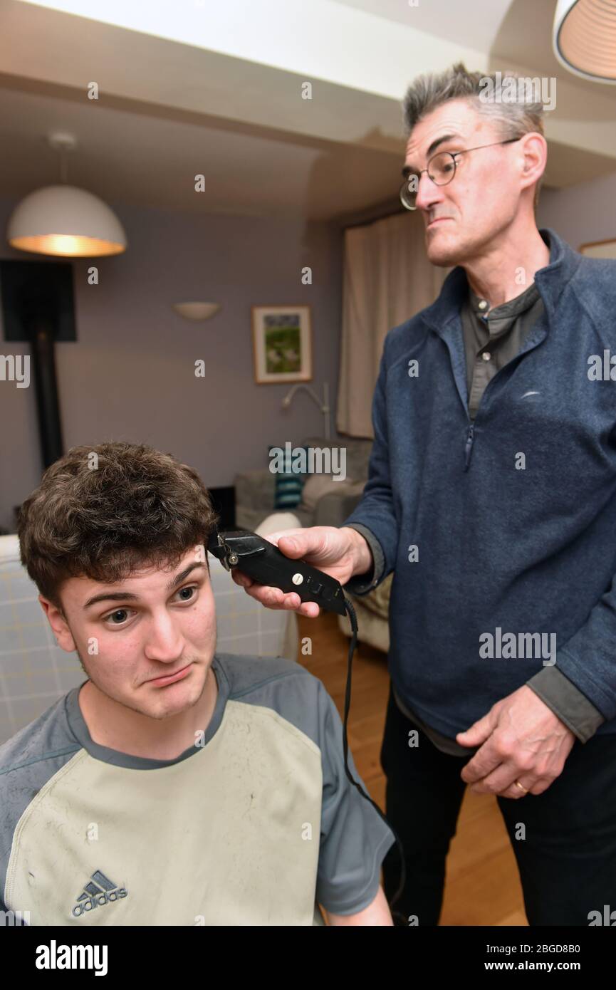 Life in Lockdown in the UK March & April 2020 A father and son cut each others hair, under lockdown using some clippers. Model released. Stock Photo