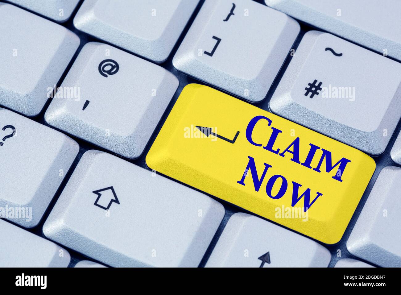 A keyboard with the words CLAIM NOW in blue lettering on a yellow enter key. Insurance, winning or pension concept. England, UK, Britain Stock Photo