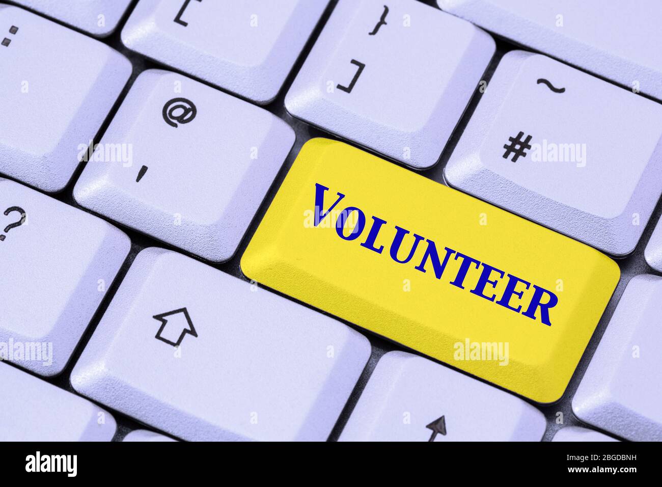 A keyboard with the word VOLUNTEER in blue lettering on a yellow enter key. Volunteering concept. England, UK, Britain Stock Photo