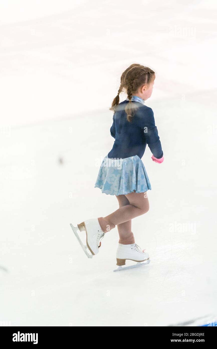 Little girl practicing figure skating on an indoor ice skating rink