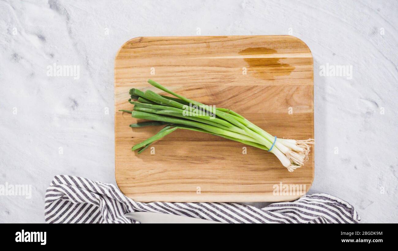 Flat lay. Step by step. Chopping organic green onions on a wood cutting ...