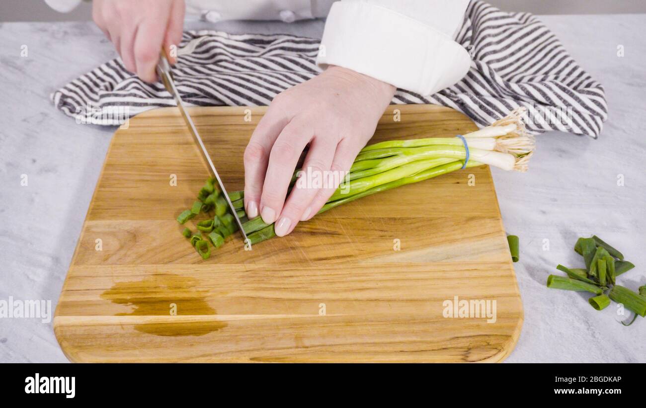 Step by step. Chopping organic green onions on a wood cutting board ...