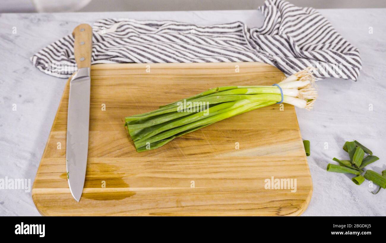 Step by step. Chopping organic green onions on a wood cutting board ...