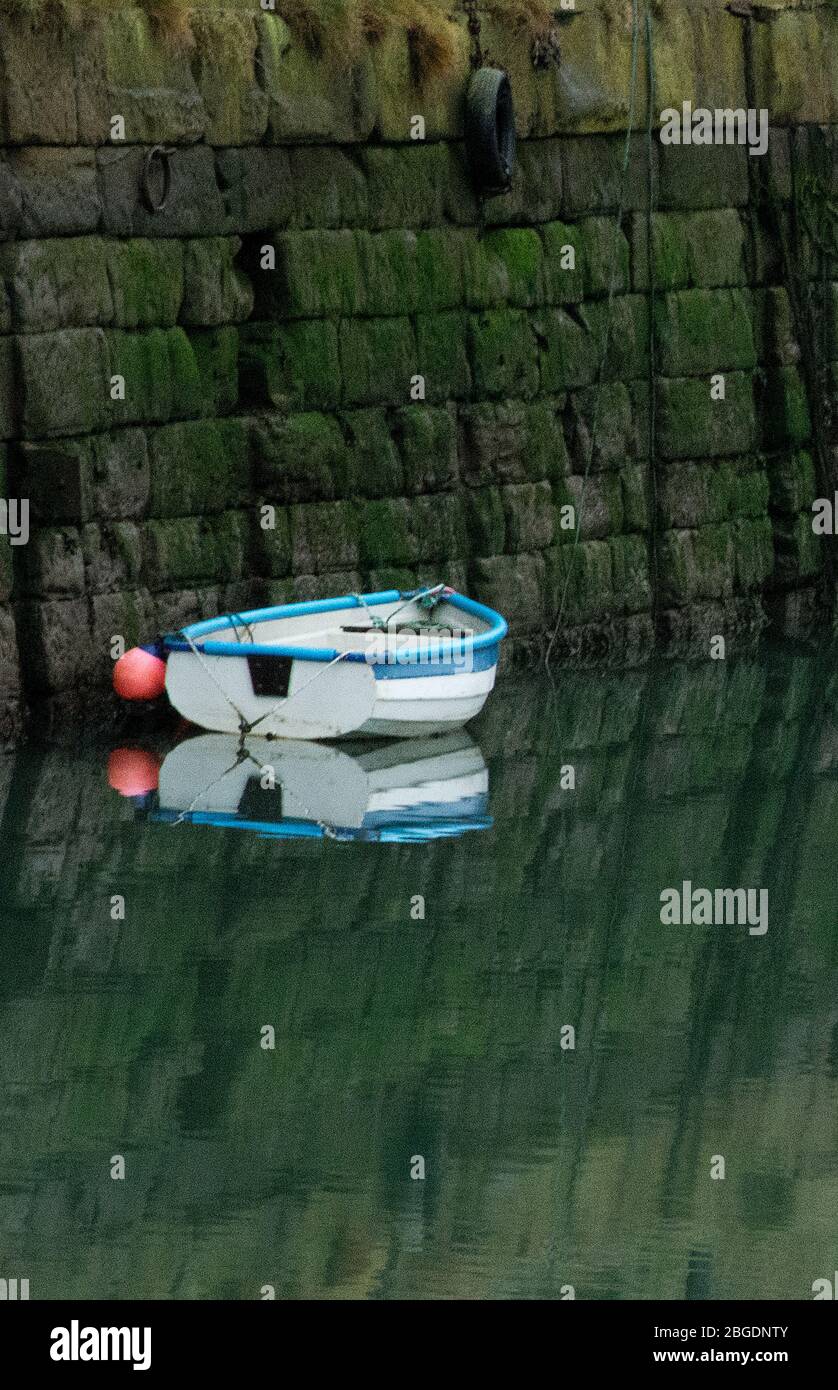 Small blue and white rowing boat with orange buoy tied up against