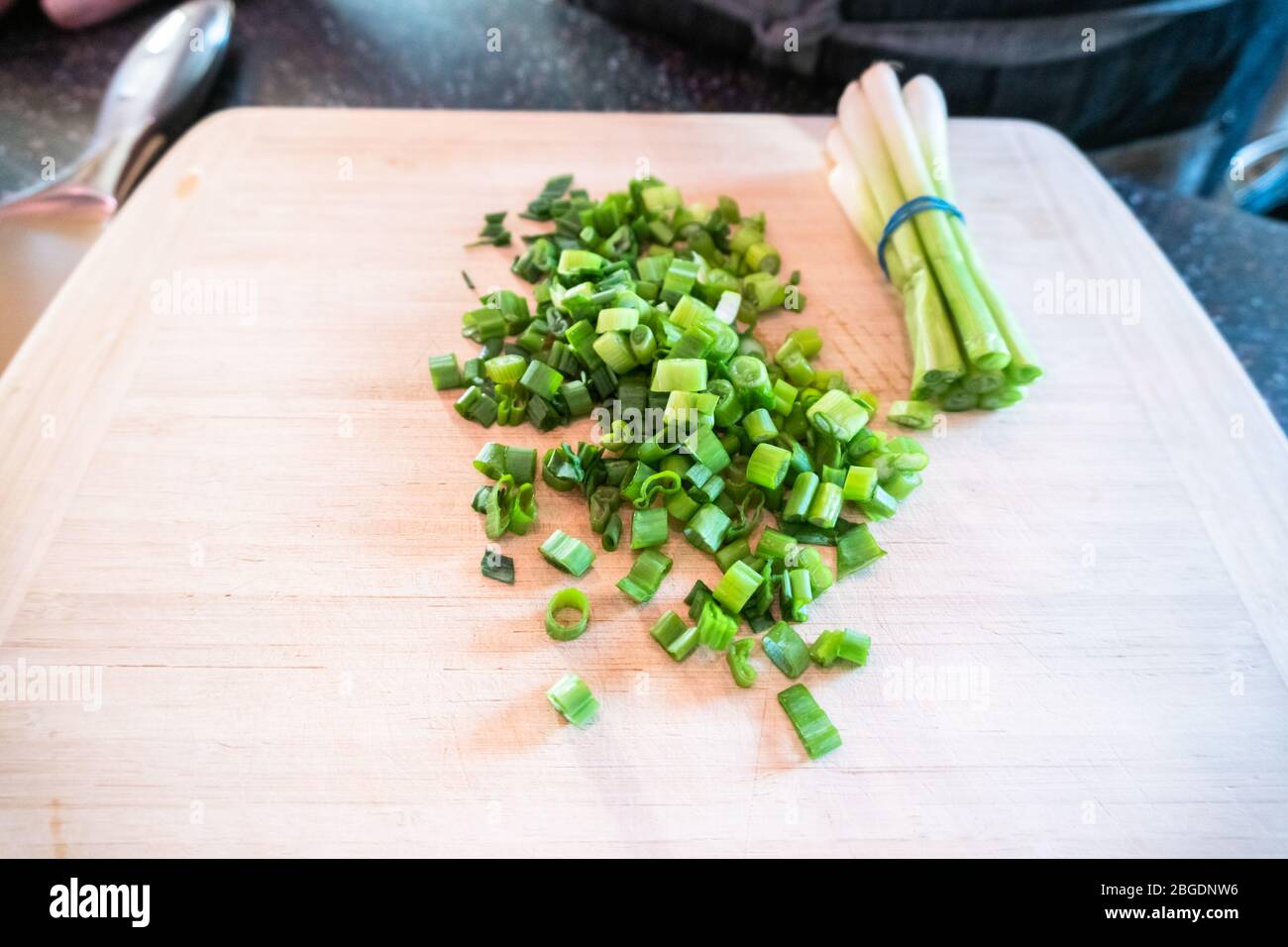 Cutting organic green onions on a wood cutting board Stock Photo - Alamy