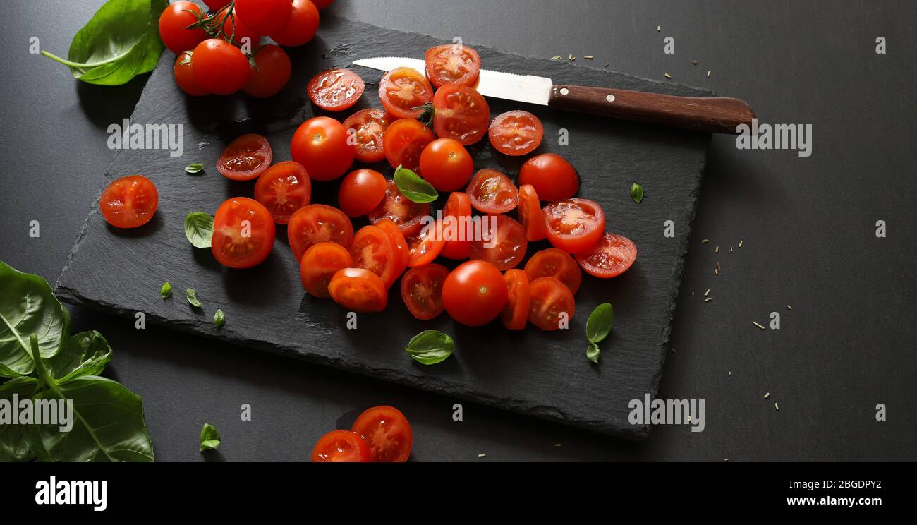 Food concept. Fresh cherry tomatoes cut on a cutting board and basil ...